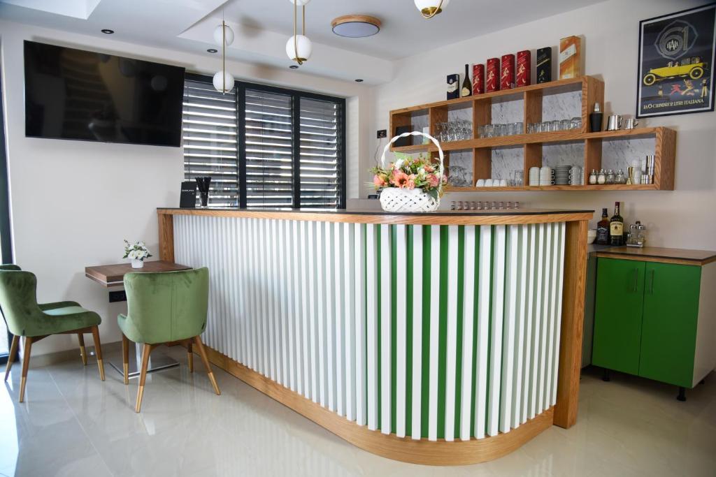 a kitchen with a bar with green chairs and a table at Merak Rooms & Caffe Bar in Šabac
