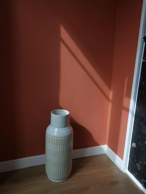 a white vase sitting on the floor next to a wall at Clos Léonie - appartement 68m2 lumineux avec sauna in Givry