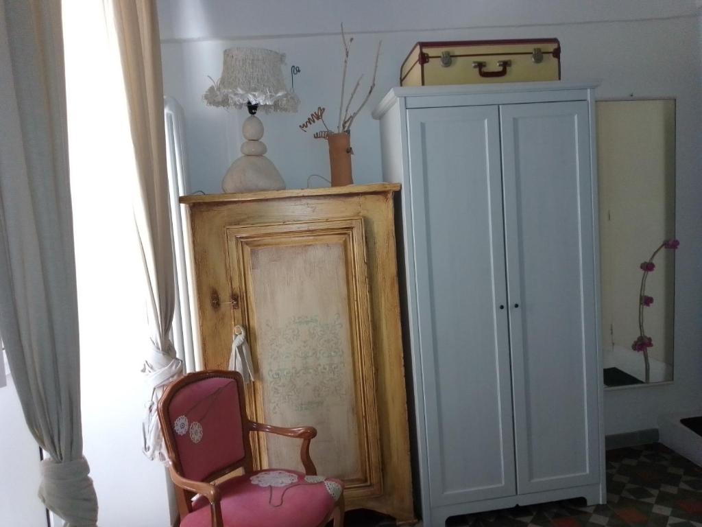 a room with a chair and a cabinet and a lamp at Malvasia room and apartment in Brindisi