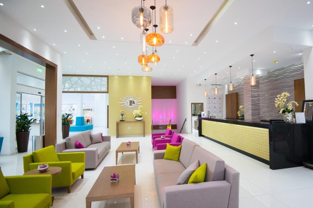 a living room with colorful chairs and couches at Loutsiana Deluxe Apts in Ayia Napa