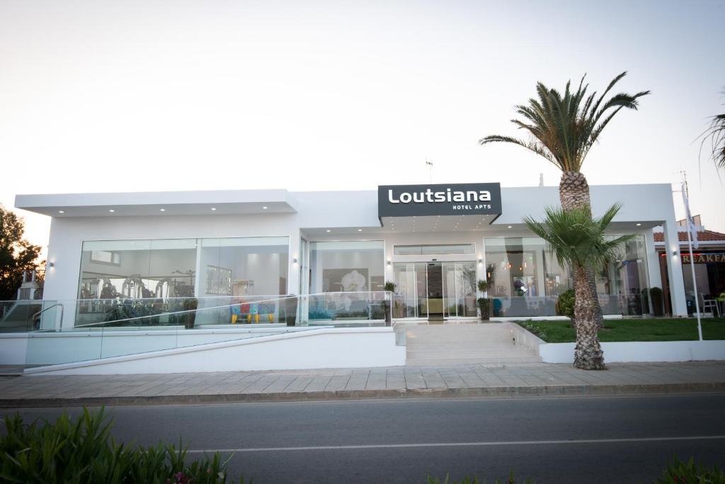 a building with a palm tree in front of it at Loutsiana Deluxe Apts in Ayia Napa