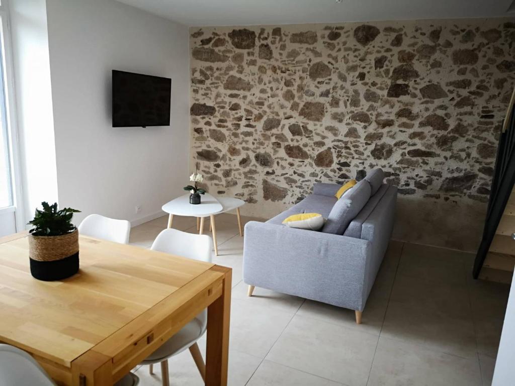 un soggiorno con divano e tavolo di Gîte O Petit Bouchon à 10 min du Puy du Fou a Sevremont