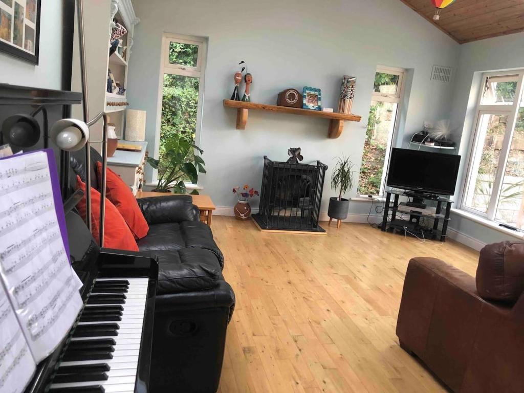 sala de estar con sofá negro y piano en The Piano House, en Carlow