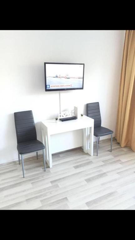 duas cadeiras sentadas ao lado de uma secretária branca com uma televisão em Apartament Tiffany em Cluj-Napoca