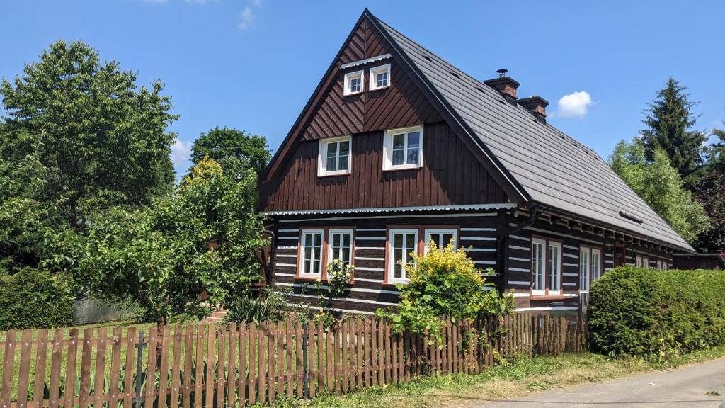 a black house with a brown roof and a fence at Wellness chata - Krkonoše in Rudník