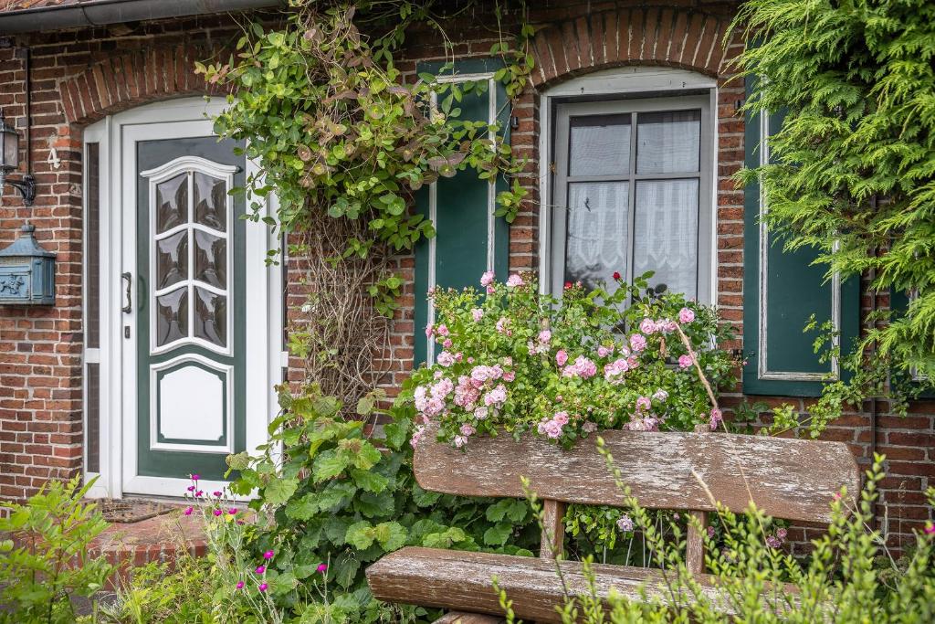 una casa con un banco con flores delante en Ferienwohnung 50027, en Wangerland