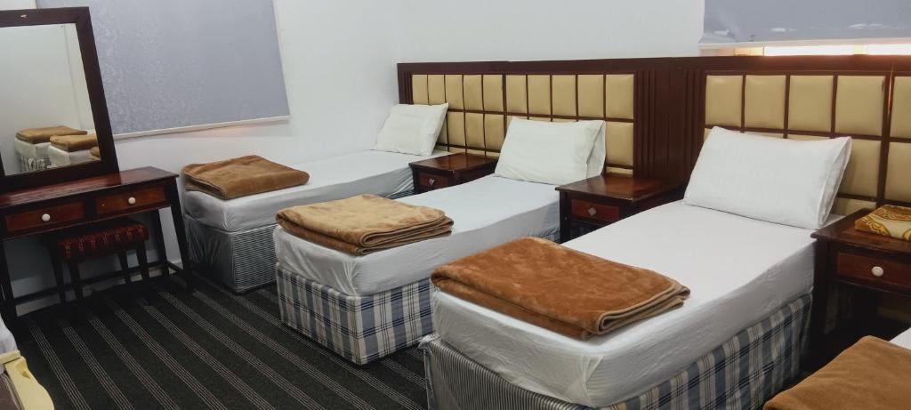 a room with three beds and a mirror at فندق الفخامة أوركيد 1 للغرف والشقق المفروشة in Makkah