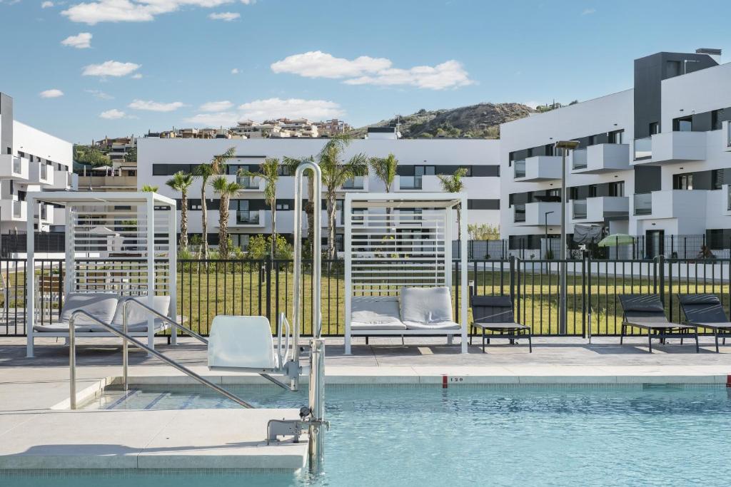 a swimming pool with chairs and a building at Residencial Celere Playa Niza in Almayate Bajo