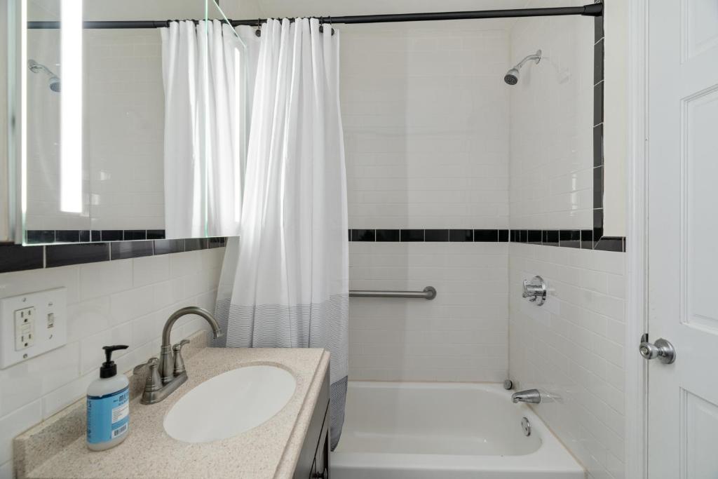 uma casa de banho branca com um lavatório e um chuveiro em City Oasis with Yard Easy Walk To Harvard MIT Train em Cambridge