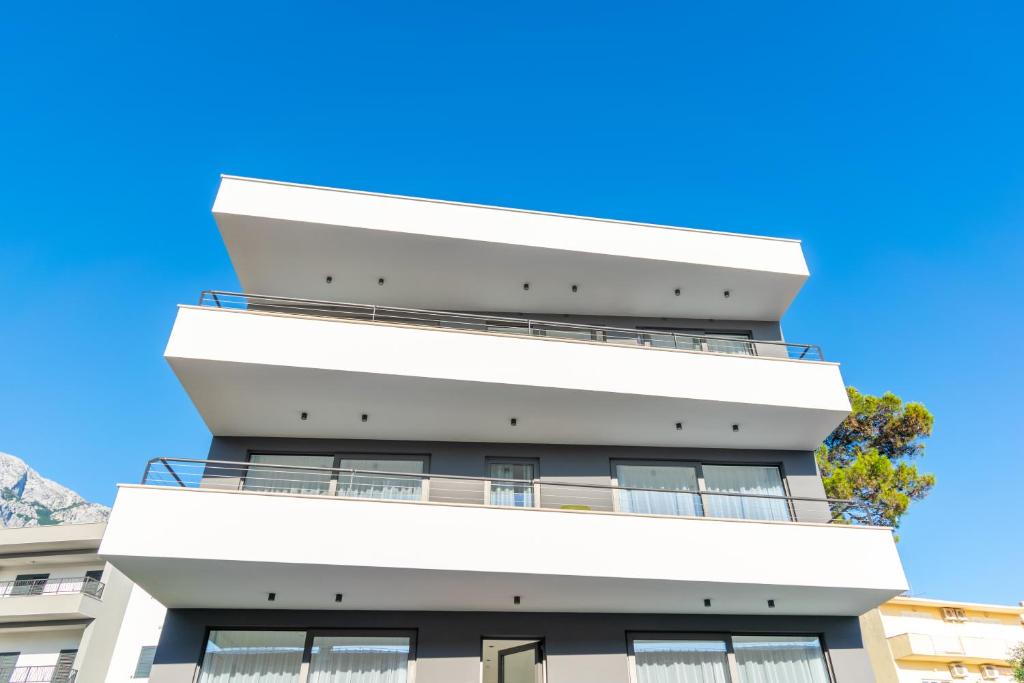 a tall white building with a blue sky in the background at Apartmani Pino 1 in Baška Voda