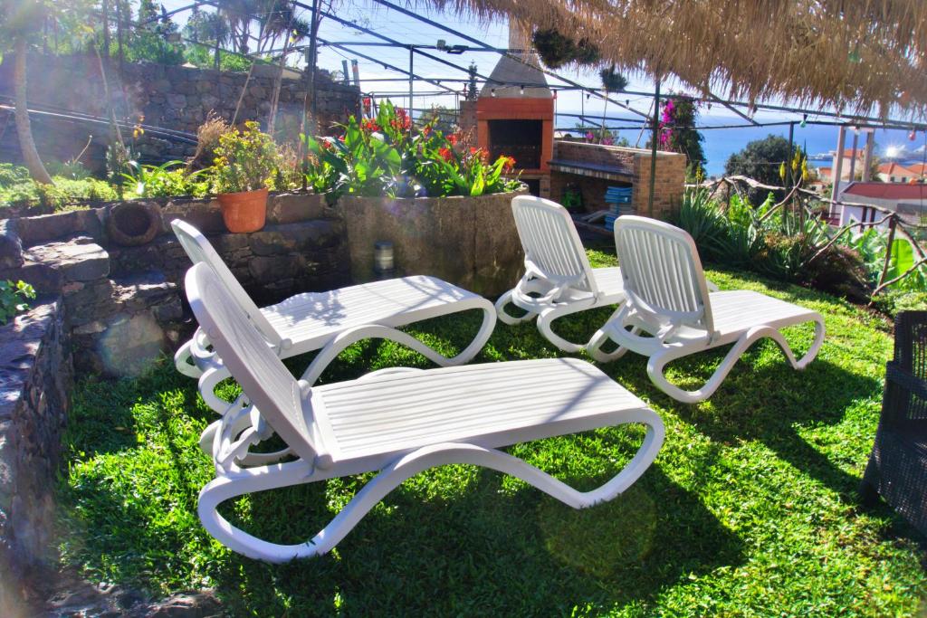 three white chairs and a table in a yard at Villa Catanho in Funchal