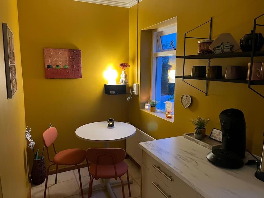a yellow kitchen with a table and chairs in it at Charming 3 bedroom apartment in Akureyri