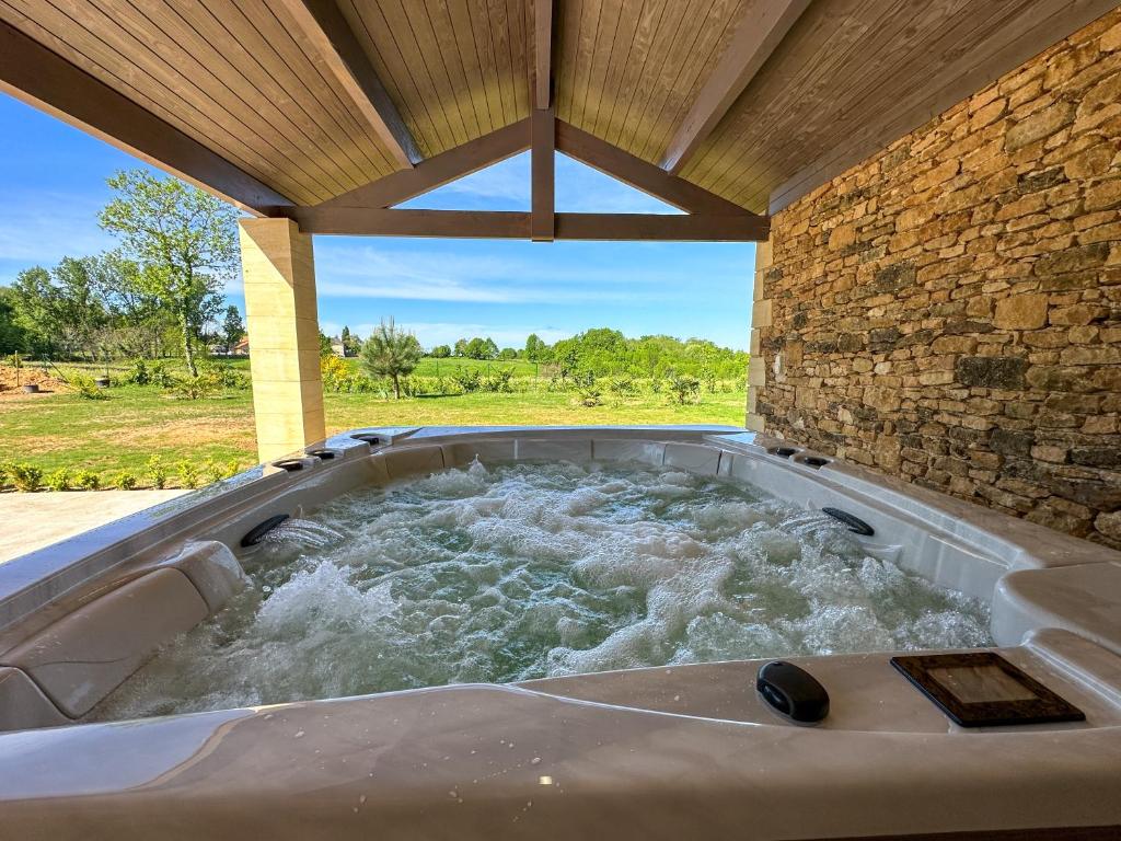 une baignoire jacuzzi avec eau et un mur en pierre dans l'établissement Villa Sarlat ,piscine/jacuzzi, à Saint-Vincent-le-Paluel