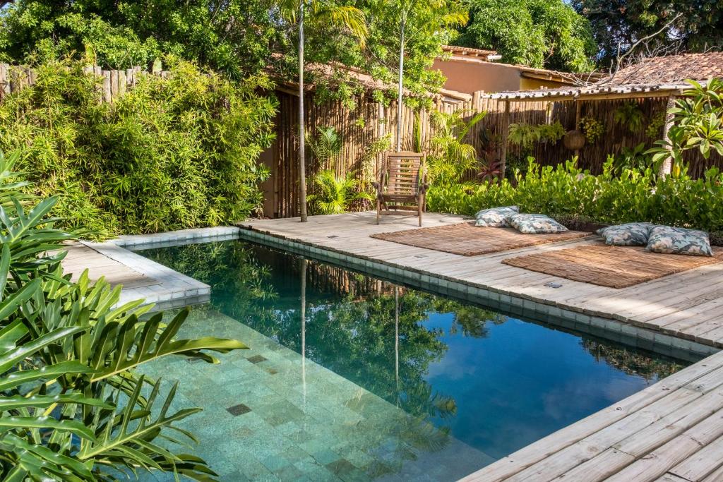 een zwembad met een terras en een stoel in de achtertuin bij Casa das Conchas Caraiva in Caraíva