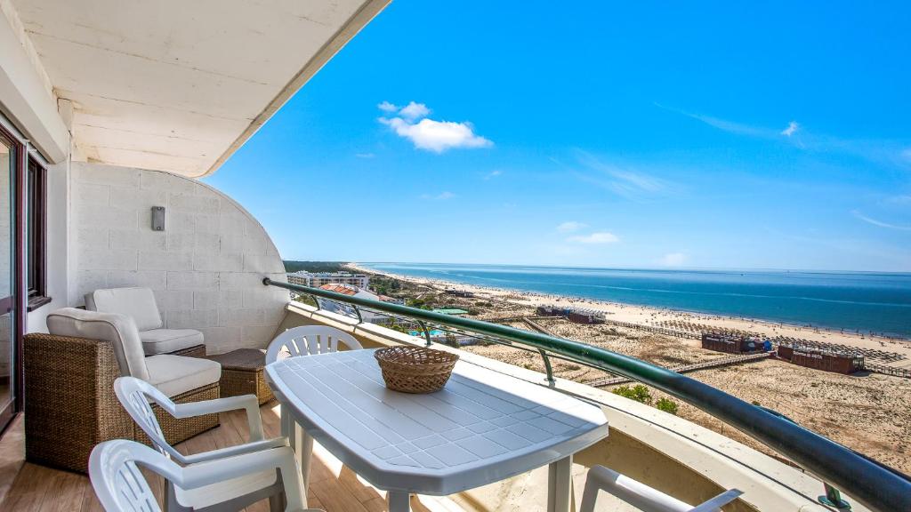 a table and chairs on a balcony with a view of the beach at 1BDR Apartment W/Beach View by LovelyStay in Monte Gordo
