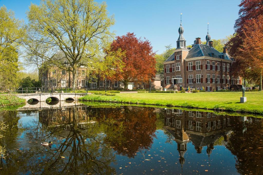 a building next to a river in front of a building at Hotel Kasteel de Essenburgh in Hierden