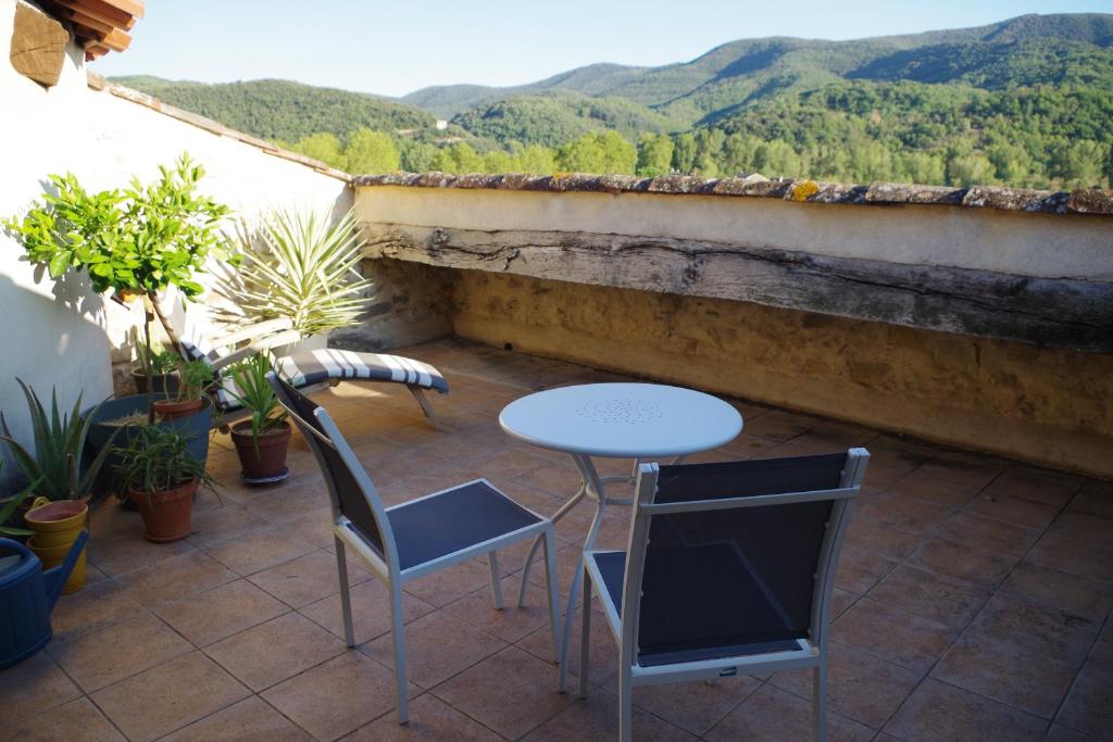 eine Terrasse mit einem Tisch, Stühlen und Bergen in der Unterkunft La Tour de l'Ange in Hérépian
