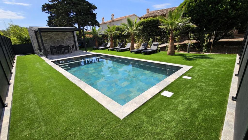 a backyard with a swimming pool and green grass at ETOILE DU BERGER Saint Aygulf 3 Villas et 4 appartements jardin individuel et piscine chauffée - la mer et les plages 450 m in Saint-Aygulf