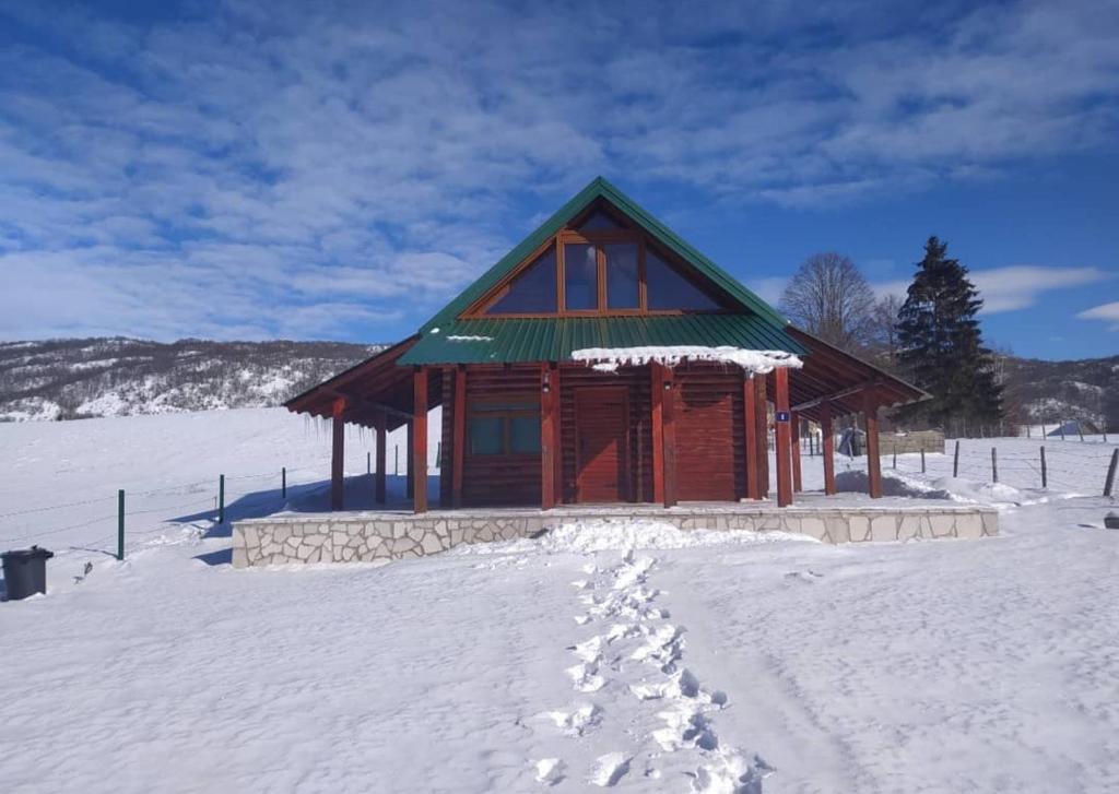 a small cabin in the snow with footprints in the snow at Planinska tišina Guest House in Pluzine