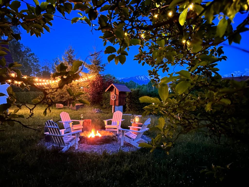 un grupo de sillas alrededor de un fuego en un patio por la noche en Cuib din Fagaras en Avrig