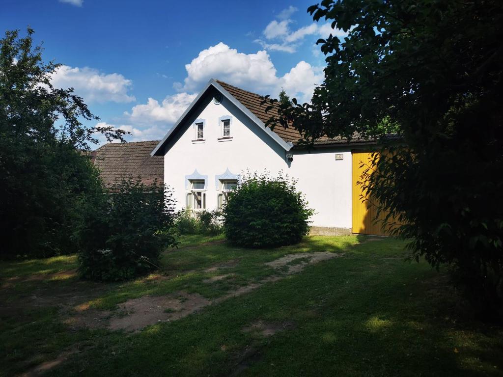 ein weißes Haus mit einem schwarzen Dach und einem Hof in der Unterkunft Chalupa Na Rachačkách in Kamenice nad Lipou