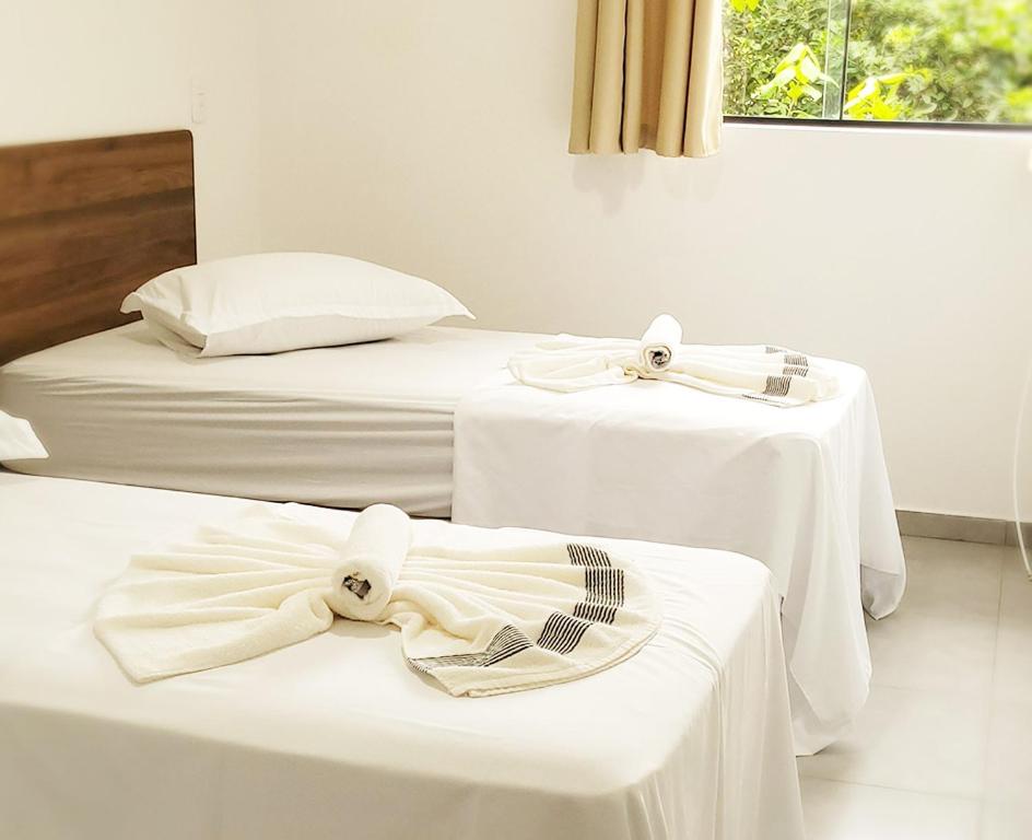 - deux lits avec des tables blanches et des nœuds papillons dans l'établissement Pousada São José, à Joinville