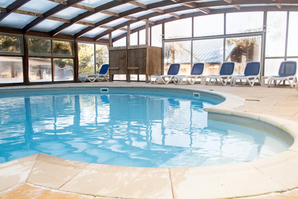 una gran piscina con sillas en un edificio en Hôtel Restaurant Domaine de l'Adoux en Saint-Jean Montclar