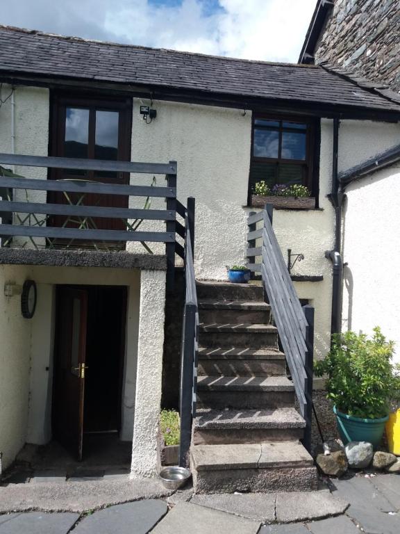 una scala che porta a una casa bianca con una porta di NEWFIELD INN a Broughton-in-Furness