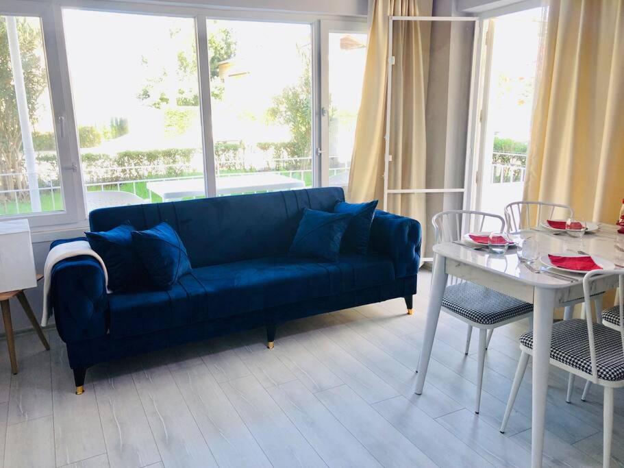 ein Wohnzimmer mit einem blauen Sofa und einem Tisch in der Unterkunft Sea View Modern Appartement with a Privet Garden in Çiftlikköy