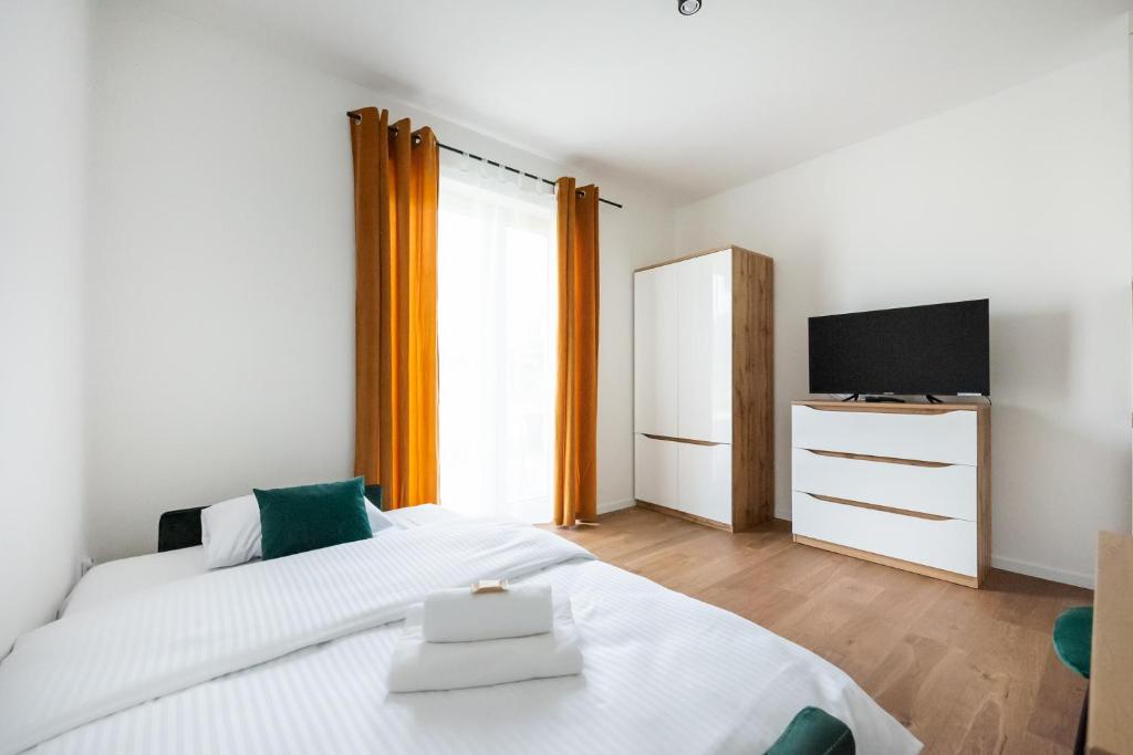 a bedroom with a large white bed and a television at HoHome Comfy Apartments in Warsaw