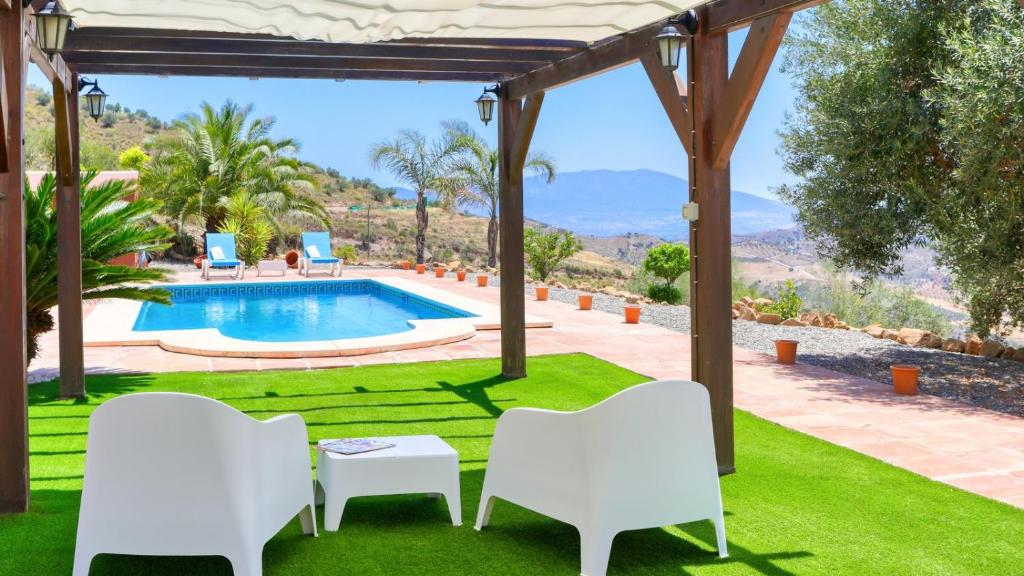patio con sedie bianche e piscina di La PacAna Álora by Ruralidays ad Alora