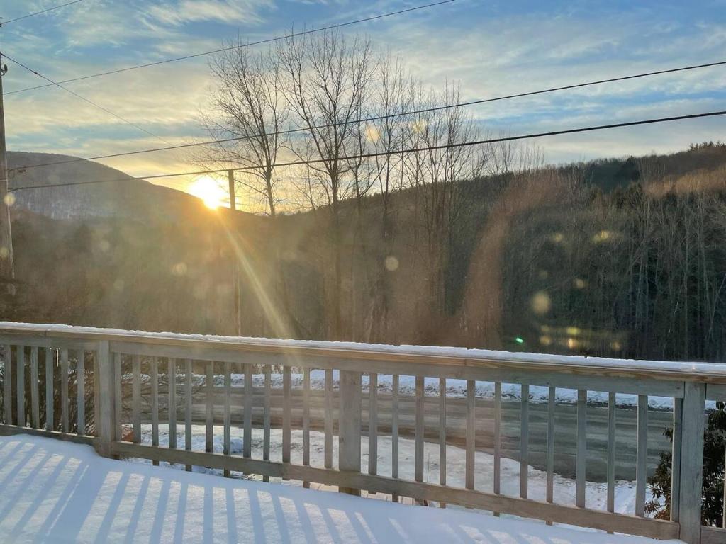 eine Winterszene, in der die Sonne hinter einem Zaun aufgeht in der Unterkunft Catskill Mountain Retreat in West Kill