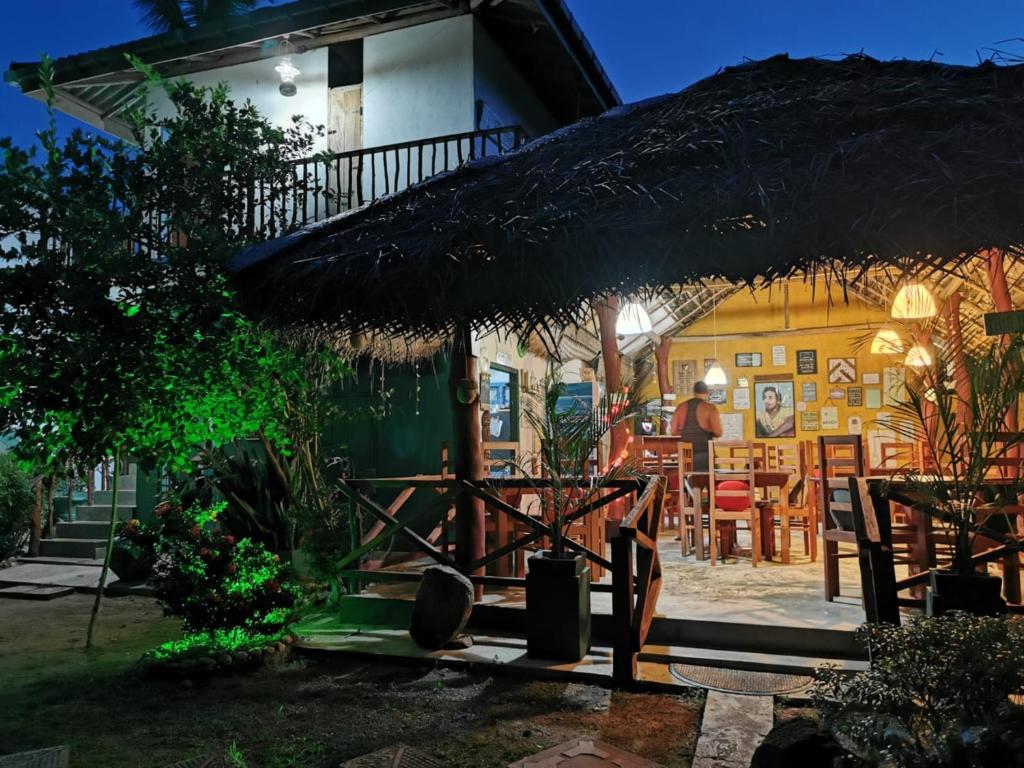dom ze słomianym parasolem i stołem w obiekcie Blue skies guest house and restaurant w Tangalli