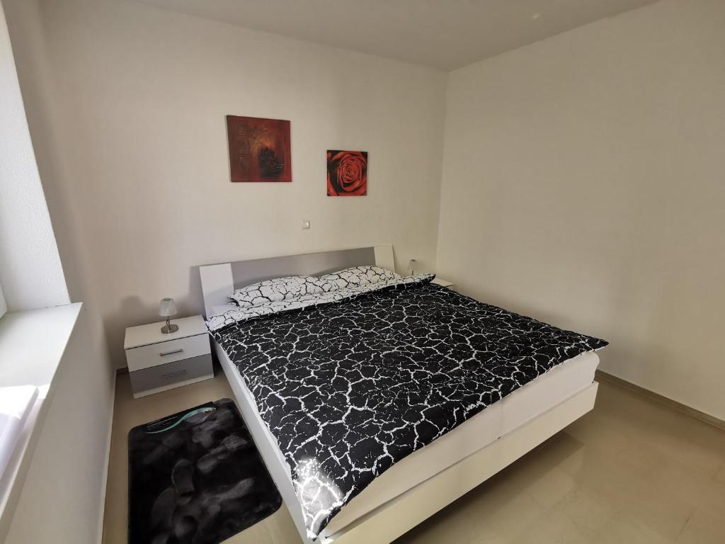 - une chambre avec un lit et une couette noire et blanche dans l'établissement Neue Bungalow Ferienwohnung, à Ansbach