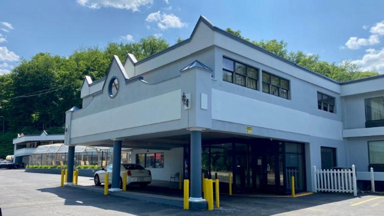 a building with a car parked in a parking lot at Days Inn by Wyndham Pittsburgh in Pittsburgh