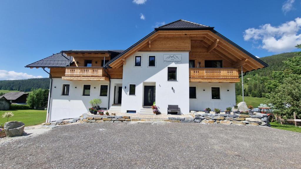 ein großes weißes Haus mit Holzdach in der Unterkunft Moamoosgut in Göriach