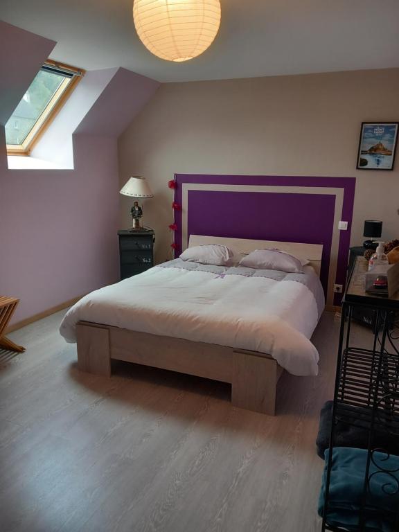 a bedroom with a large bed with a purple headboard at Chambre d&#39;hôte de la baronne in Roz-sur-Couesnon