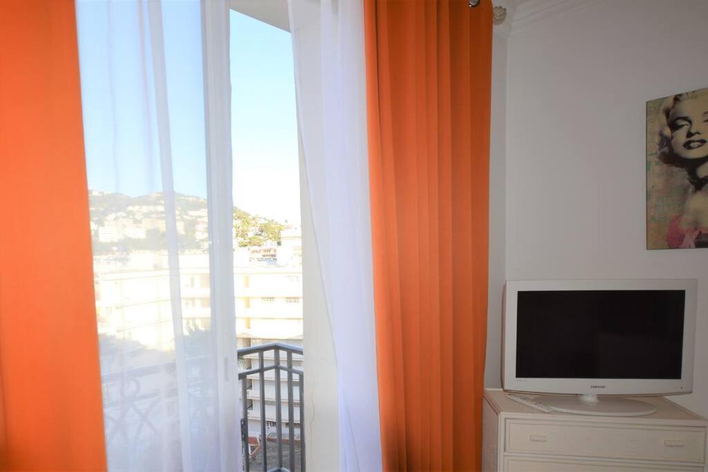 a television sitting on a dresser next to a window at Palais Miramar - Suite White Jardin - 20m Plage in Cannes
