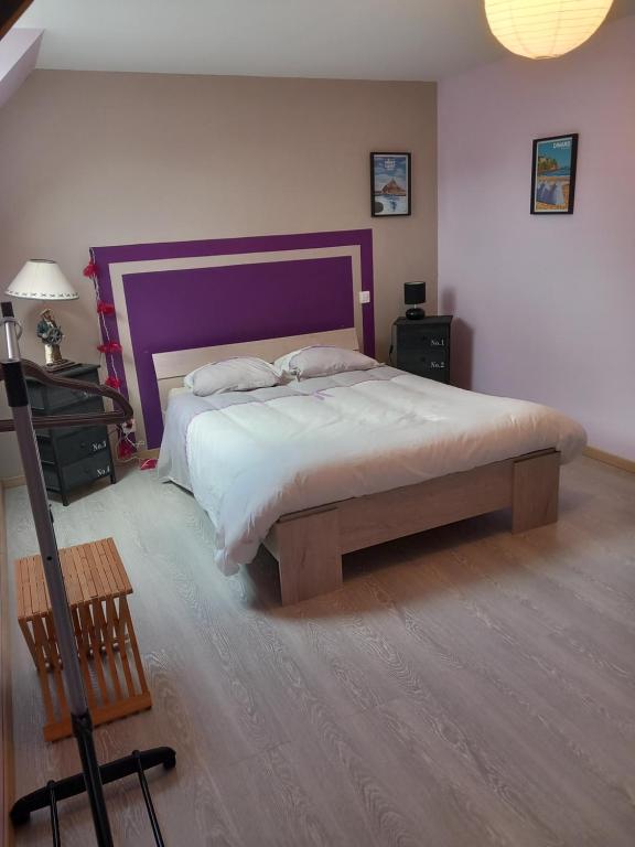 a bedroom with a large bed with a purple headboard at Chambre d&#39;hôte de la baronne in Roz-sur-Couesnon