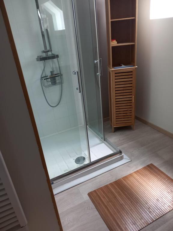 a shower with a glass door and a wooden floor at Chambre d&#39;hôte de la baronne in Roz-sur-Couesnon