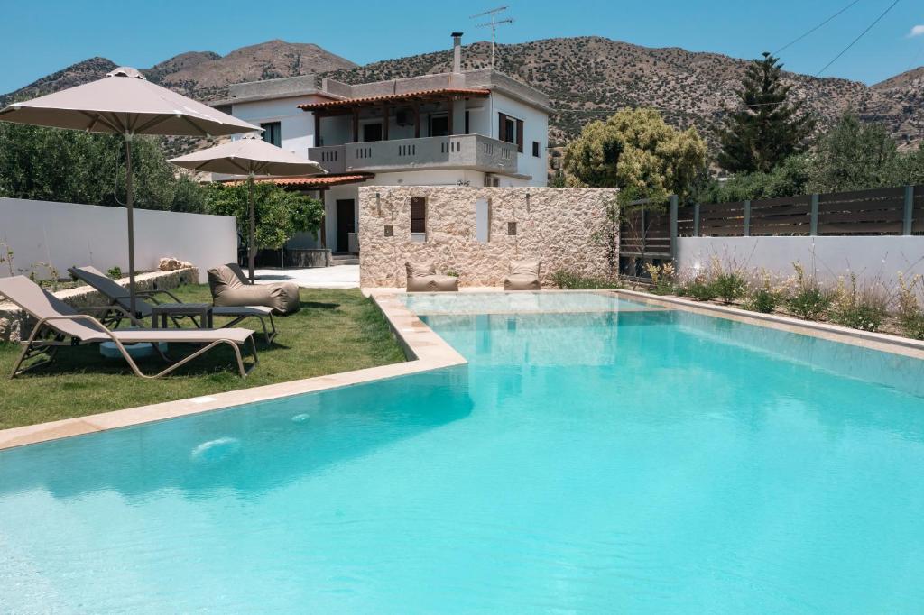 a swimming pool with chairs and a house at Villa Vigla Keratokampos in Keratokampos
