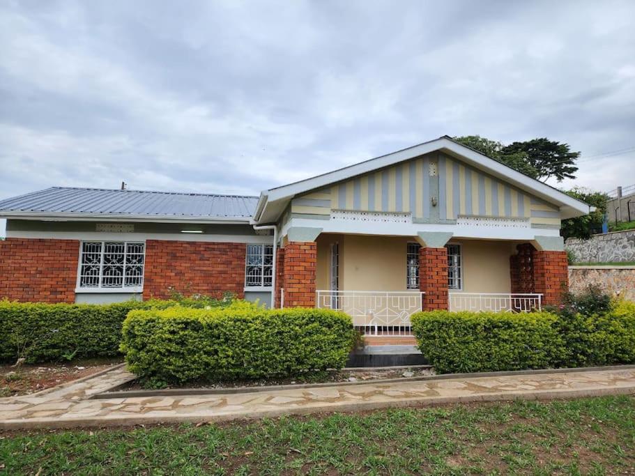 una casa de ladrillo con arbustos delante de ella en Harukooto Suites en Fort Portal