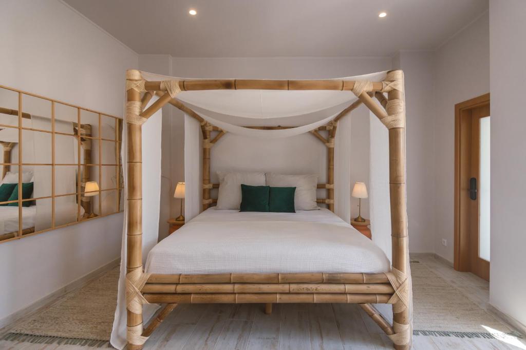 Schlafzimmer mit einem hölzernen Himmelbett und grünen Kissen in der Unterkunft Aldeia de Portimão in Portimão