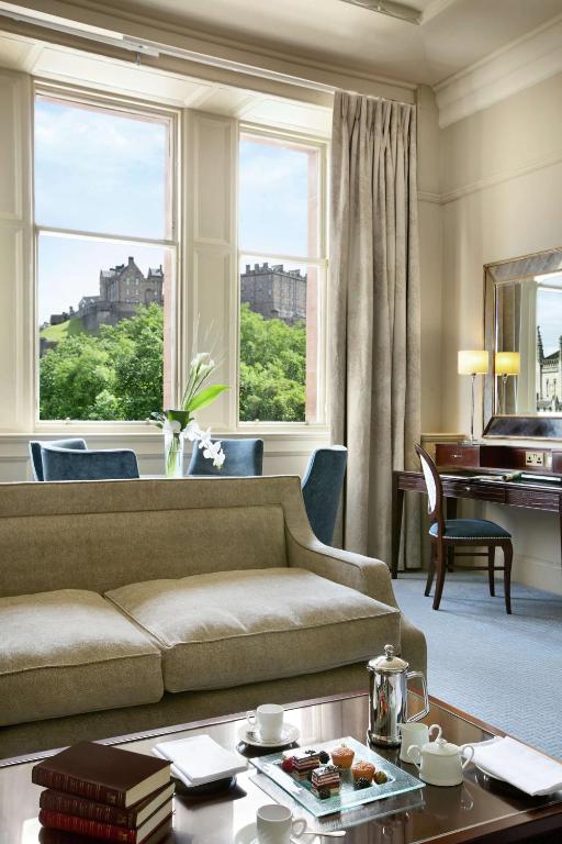 a living room with a couch and a piano at The Caledonian Edinburgh, Curio Collection by Hilton in Edinburgh