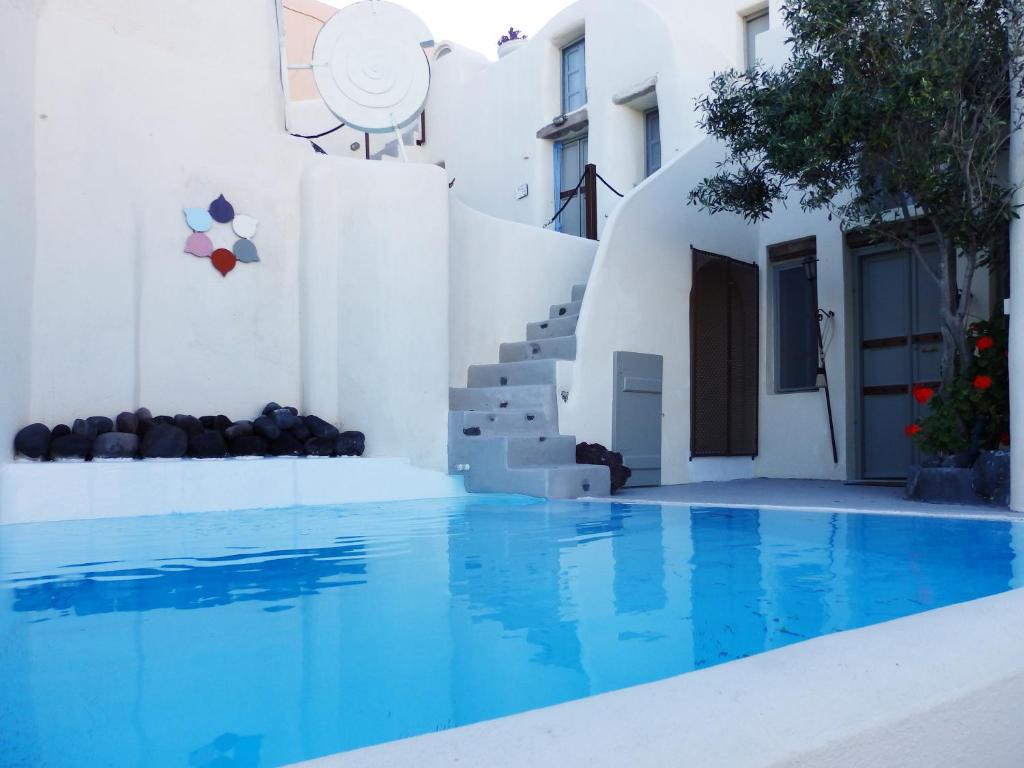 een zwembad met blauw water voor een wit gebouw bij Timedrops Santorini Villas in Emporio