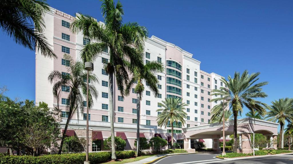a large white building with palm trees in front of it at DoubleTree by Hilton Sunrise - Sawgrass Mills in Sunrise
