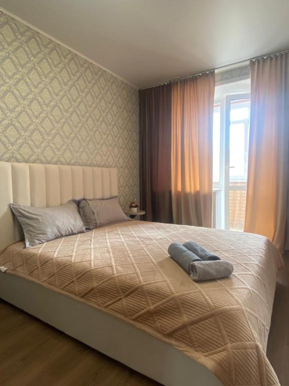 1 cama grande en un dormitorio con ventana en Комфортабельные - Уютные апартаменты в Костанай Алтын Арман, en Kostanái