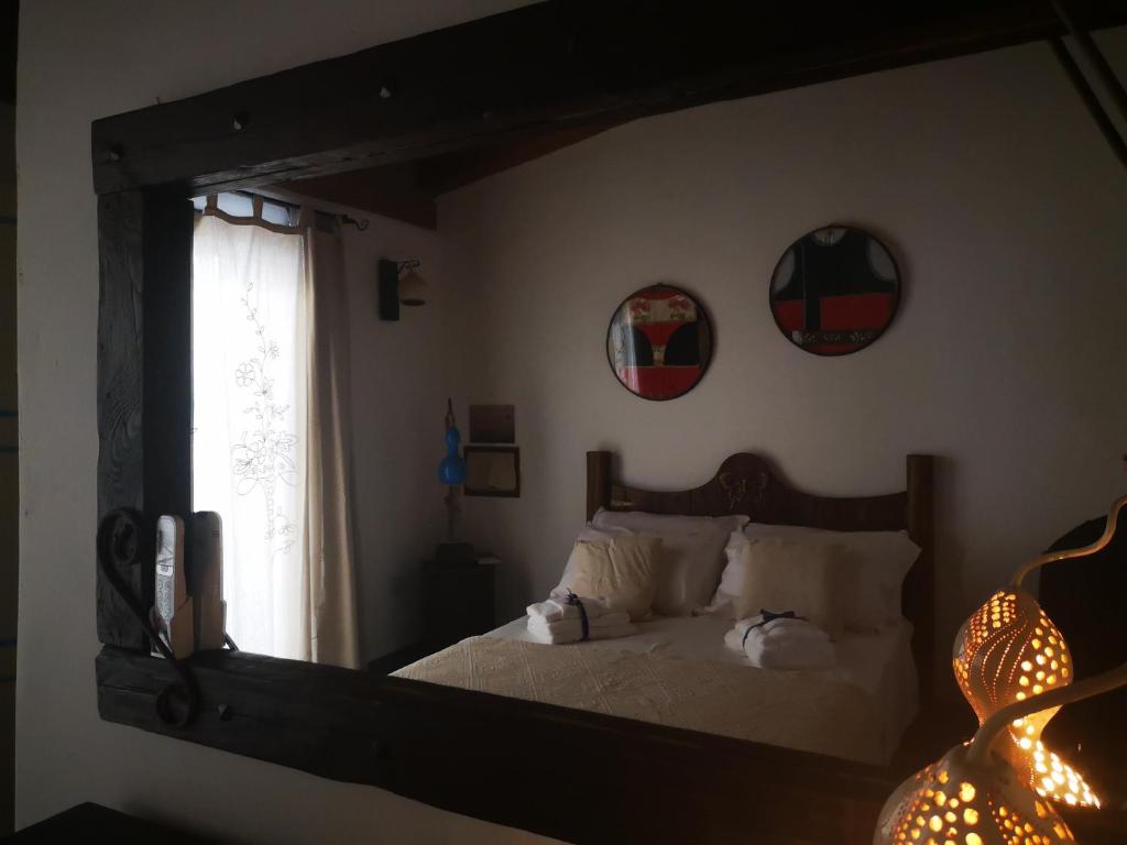 a mirror reflecting a bedroom with a bed and a window at Domo Dizósa in Siniscola