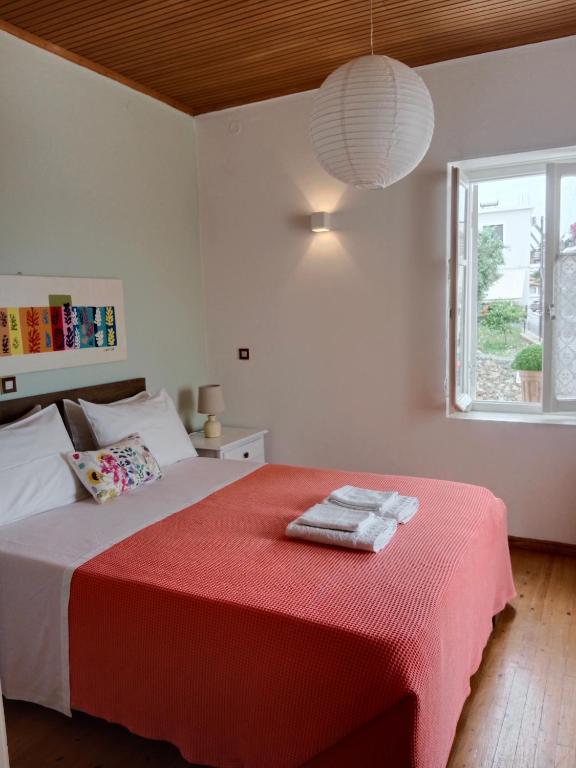 a bedroom with a bed with a red blanket and a window at George Traditional House in Pylos