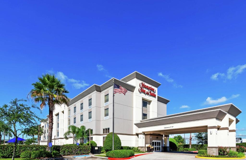 a hotel with an american flag in front of it at Hampton Inn & Suites Houston-Bush Intercontinental Airport in Houston